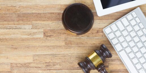 A gavel sits on a desk next to a computer keyboard and a coffe cup.
