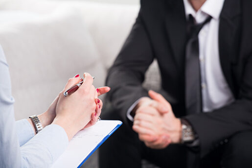 Two people sit across from each other with clasped hands.