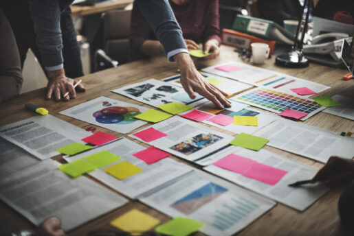 Individuals working over a spread of papers and diagrams spread out on a conference table.