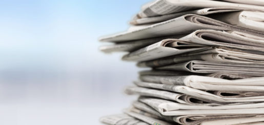 A stack of newspapers on the right with a blurred out blue background.