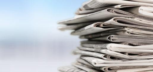 A stack of newspapers on the right against a blue blurry background.