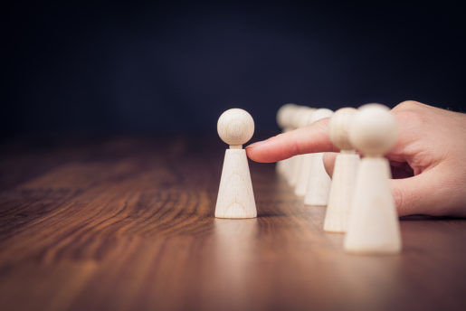 A hand pushes a white pawn forward out of a row.