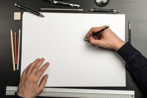 Two hands about to begin sketching on a blank piece of paper.