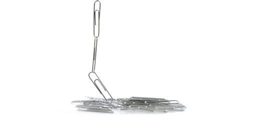 Paperclips linked together fall into a pile against a white background.
