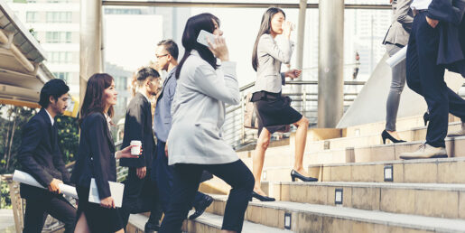 Image of various Asian individuals in a corporate setting climbing up stairs in a building.