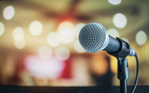 Microphone stands out against a blurred lit up background.