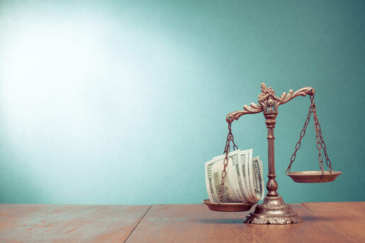 Scales sit on a desk with money on one side weighing it down.